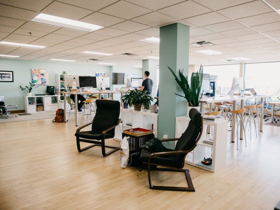 Open coworking aread with standing and seated desks, monitors, and comfortable seating.